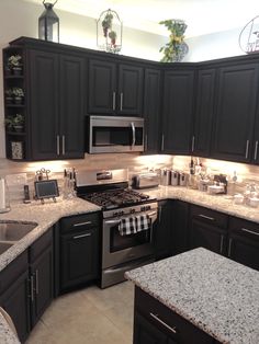 a kitchen with granite counter tops and stainless steel appliances in the center, along with dark wood cabinets