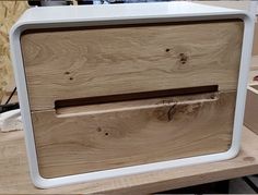 a wooden cabinet with a white handle on the front and bottom part, sitting on top of a workbench