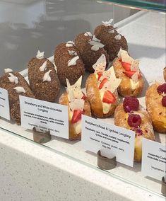 there are many pastries on display in the glass case at the store, including strawberries and other fruit