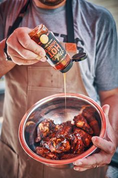 a man pouring sauce on food in a bowl