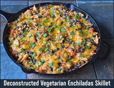 a skillet filled with mexican enchiladas and green onions on the side