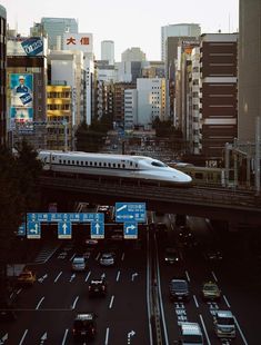 a train traveling over a bridge in the middle of a city with lots of traffic