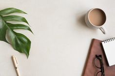 a cup of coffee, pen and eyeglasses on a desk next to a notebook