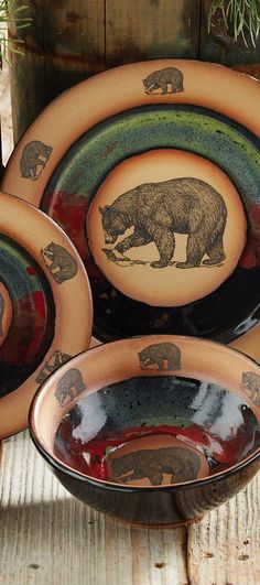 three brown and green plates with bears painted on them, sitting next to each other