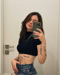 a woman taking a selfie in the mirror with her cell phone and tattoos on her stomach