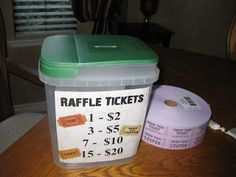 a plastic container with raffle tickets sitting on a table next to a roll of toilet paper