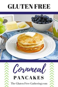 a white plate topped with pancakes covered in butter and blueberries next to a bowl of grapes