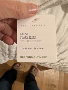 a person holding up a white label that says leaf pillow cover