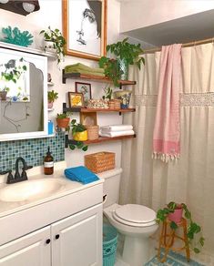 a white toilet sitting under a bathroom mirror next to a sink and a shower curtain