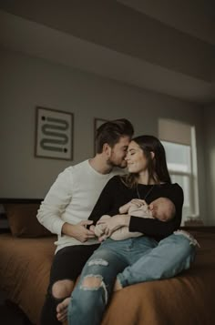 a man and woman sitting on top of a bed holding a baby in their arms