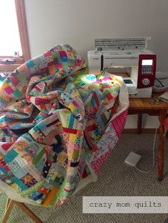 a quilted blanket sitting on top of a table next to a sewing machine