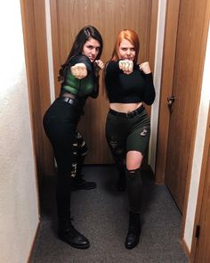 two women dressed in black and green posing for the camera with their fists up while standing next to each other