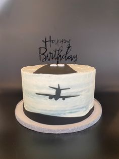 a birthday cake with an airplane painted on the side and happy birthday written on top