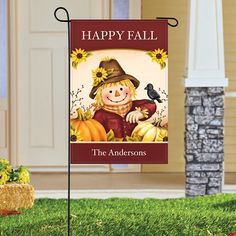 a happy fall garden flag with a scarecrow and pumpkins in the background on grass