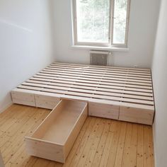 an empty bed with drawers on the bottom is shown in this room, and there are no people around it