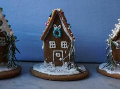 three gingerbread houses decorated with icing and decorations on top of snow covered ground