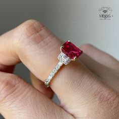 a woman's hand holding an engagement ring with a pink tourmaline stone