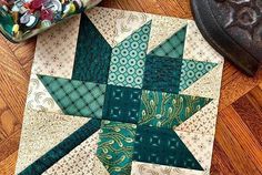 a green and white quilted star sitting on top of a wooden floor next to a container of candy