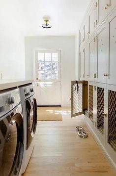 a washer and dryer in a room with white walls, wood floors and cabinets