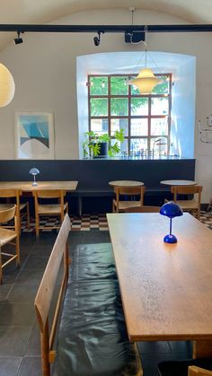 an empty restaurant with wooden tables and chairs in front of a large window on the wall