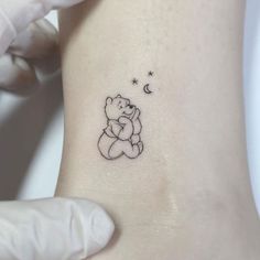 a small teddy bear tattoo on the left side of the right arm, with stars and moon above it