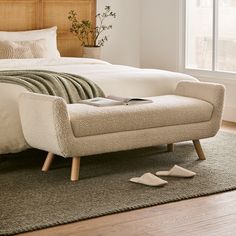 a bedroom with a bed, chair and footstool in front of a window