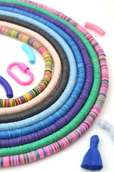 a bunch of different colored beads and scissors on a white surface with some tassels