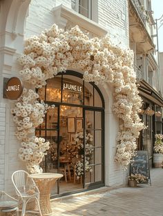 a white chair sitting in front of a store with lots of flowers hanging from it's windows