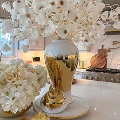 a vase with flowers in it sitting on a table next to a gold and white plate