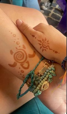 a woman's arm with hendi tattoos and bracelets on her left wrist