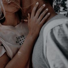 a man and woman kissing each other with trees in the background