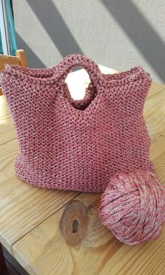 a crocheted bag sitting on top of a wooden table next to a ball of yarn