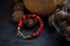 an orange and black beaded bracelet next to some nuts on a table with a pumpkin in the background