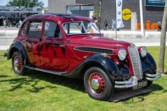 an old red car is parked in the grass