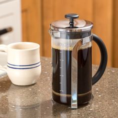 a french press coffee maker sitting on top of a kitchen counter next to a mug