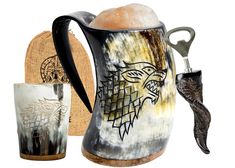 a game of thrones themed pitcher and two mugs with handles are shown next to each other