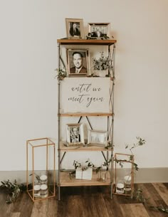 a shelf with pictures, candles and photos on it in front of a white wall