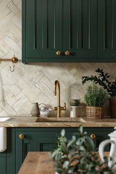 a kitchen with green cabinets and marble backsplash, gold faucet handles