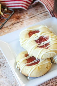 two cookies with white icing and strawberry jam on top are sitting on a plate