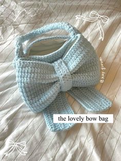 a crocheted bag with a large bow on it's side sitting on a bed