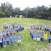 a group of people standing on top of a lush green field next to each other