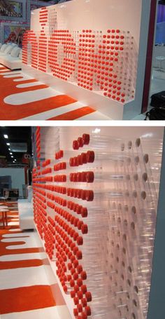 an orange and white wall with rows of chairs in the background at a trade show