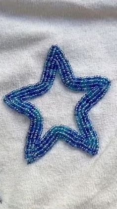 a blue beaded star sitting on top of a white shirt