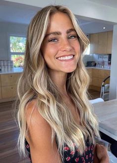 a woman with long blonde hair standing in front of a dining room table and looking at the camera