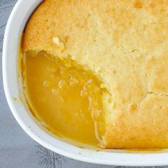 a close up of a pie in a white bowl on a gray table cloth with a spoon