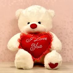 a white teddy bear holding a red heart with the words i love you on it