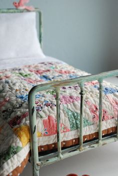 an old iron bed frame with colorful quilts on it