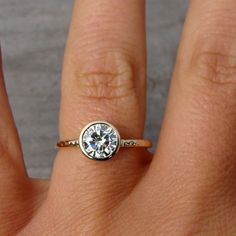 a woman's hand with a diamond ring on top of her finger, showing the center stone