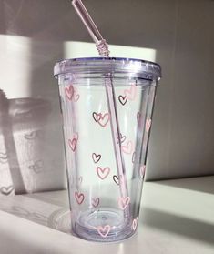 a cup with two straws in it and hearts on the side, sitting on a counter