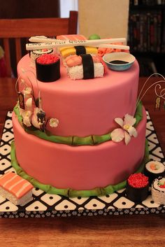 a pink cake decorated with sushi and chopsticks